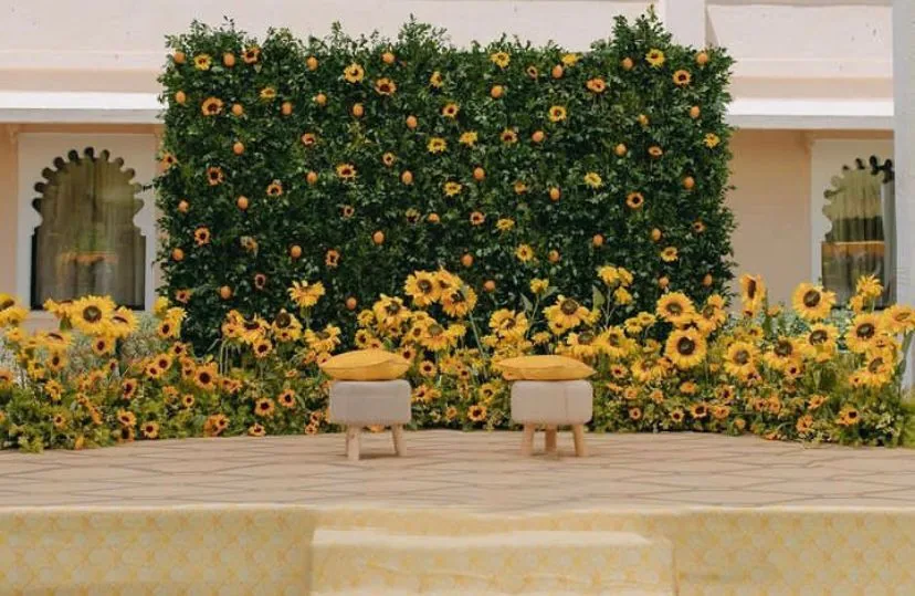 Sunflower wall backdrop behind two low seats for a haldi — event by Plan With YOLO, Pune