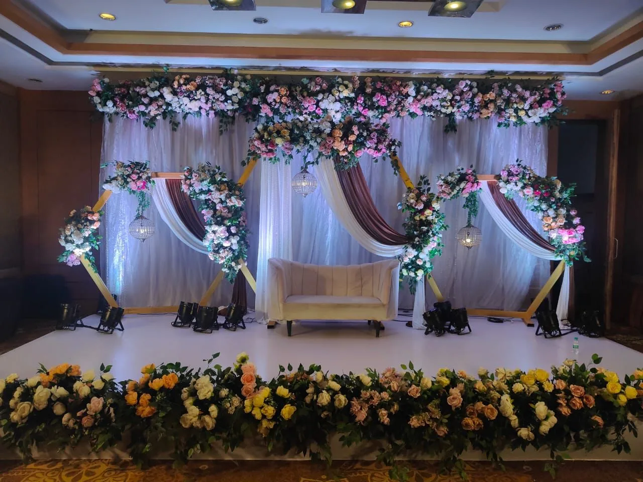 Floral arches and a sofa on the banquet stage — event by Plan With YOLO, Pune