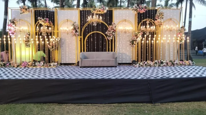 Reception stage built on a lawn, gold arches — event by Plan With YOLO, Pune